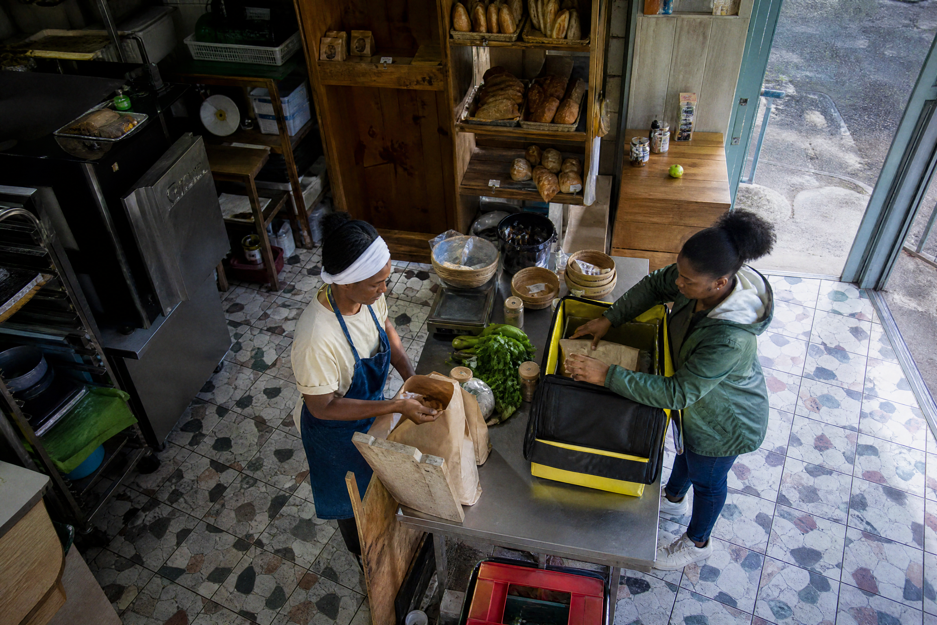 Un commerce de quartier prépare les commandes avec un artisan et une livreuse en Martinique.
